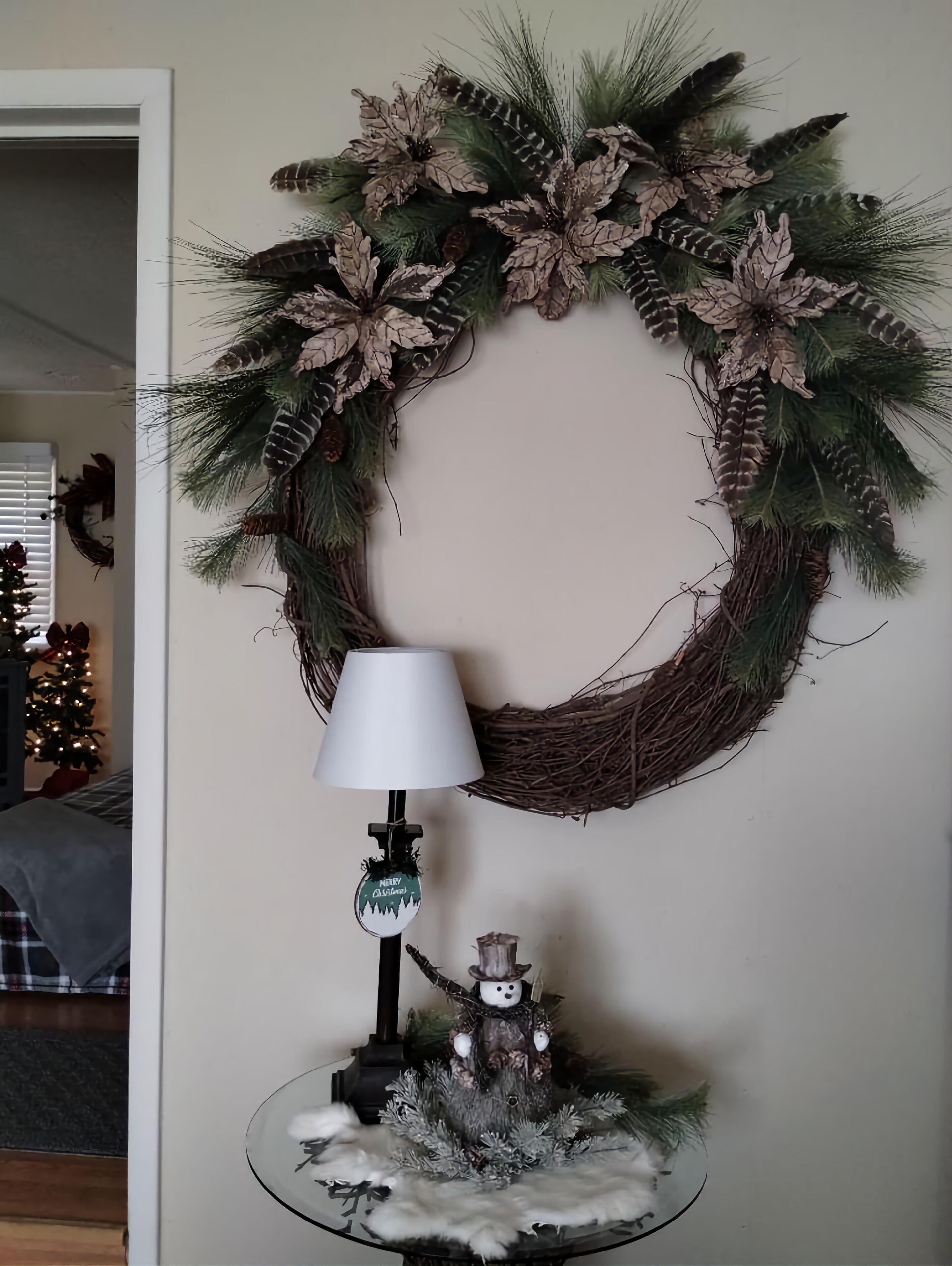 Una guirnalda con piñas y follaje, una lámpara y una decoración de muñeco de nieve sobre una mesa.