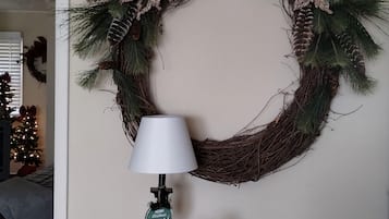 Una guirnalda con piñas y follaje, una lámpara y una decoración de muñeco de nieve sobre una mesa.