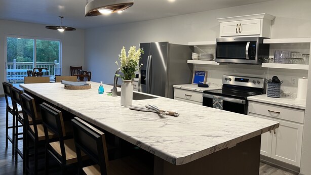 Una cocina moderna con una isla de mármol, electrodomésticos de acero inoxidable y un comedor con sillas de madera.