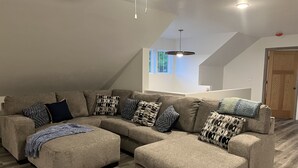 Una sala moderna con un sofá modular, cojines decorativos estampados y suelo de madera.