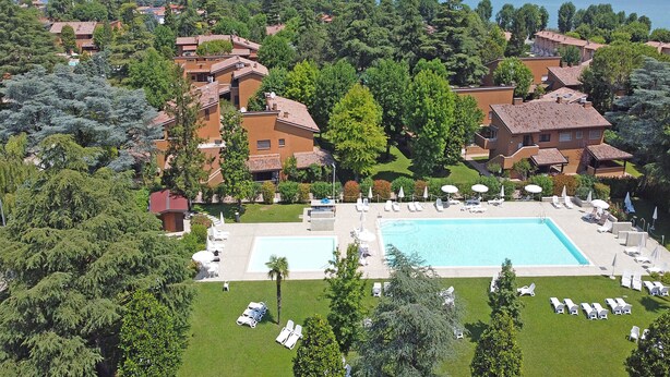 Ein Resort mit mehreren Gebäuden, einem großen Schwimmbad und Blick auf das Meer.
