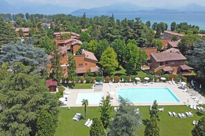 Ein Resort mit mehreren Gebäuden, einem großen Schwimmbad und Blick auf das Meer.