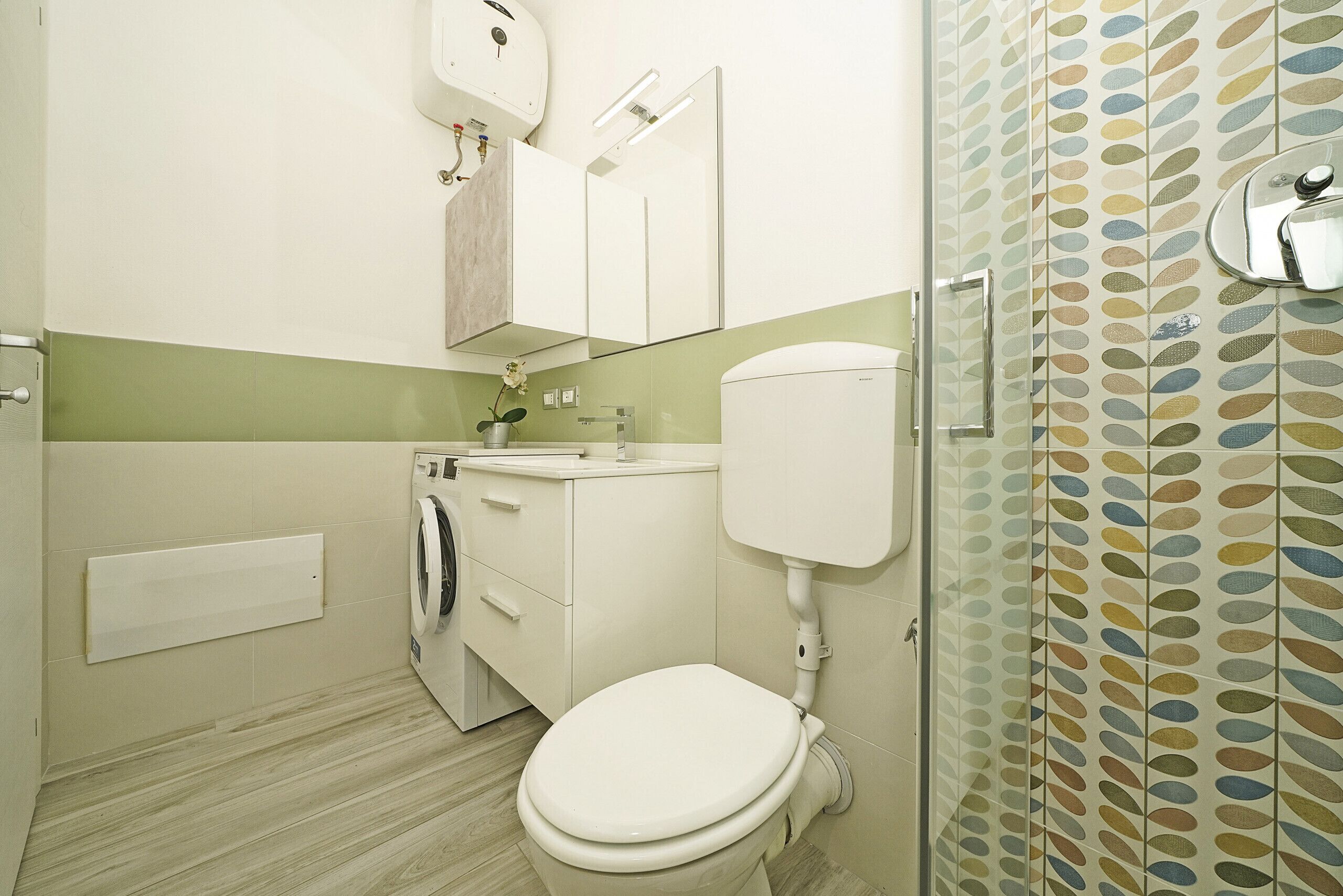 A bathroom with a toilet, washing machine, and sink.