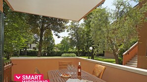 Eine Terrasse im Freien mit einem Holztisch, Stühlen und einer Weinflasche.