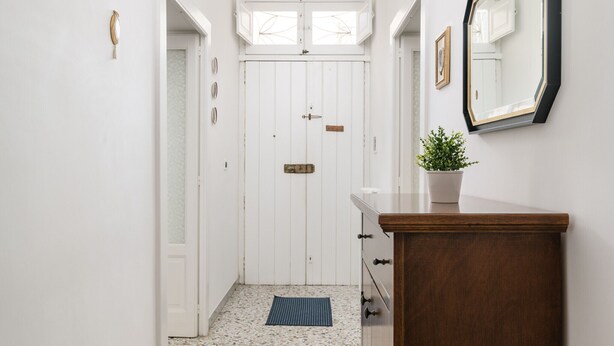 A hallway with a white door, a mirror, and a wooden cabinet.