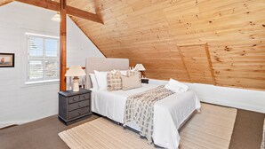 A bedroom with a sloped ceiling, a bed with white bedding, a nightstand with a lamp, and a window with blinds. - Anembo Hideaway - Relaxing Oasis (Kiama Heights)