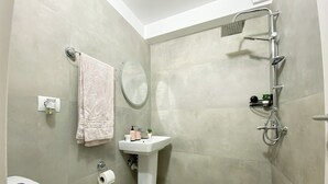 A bathroom with a toilet, sink, shower, towel, and a mirror. - Room-three Doors Apartments, Papaya 1-be (Tirana)