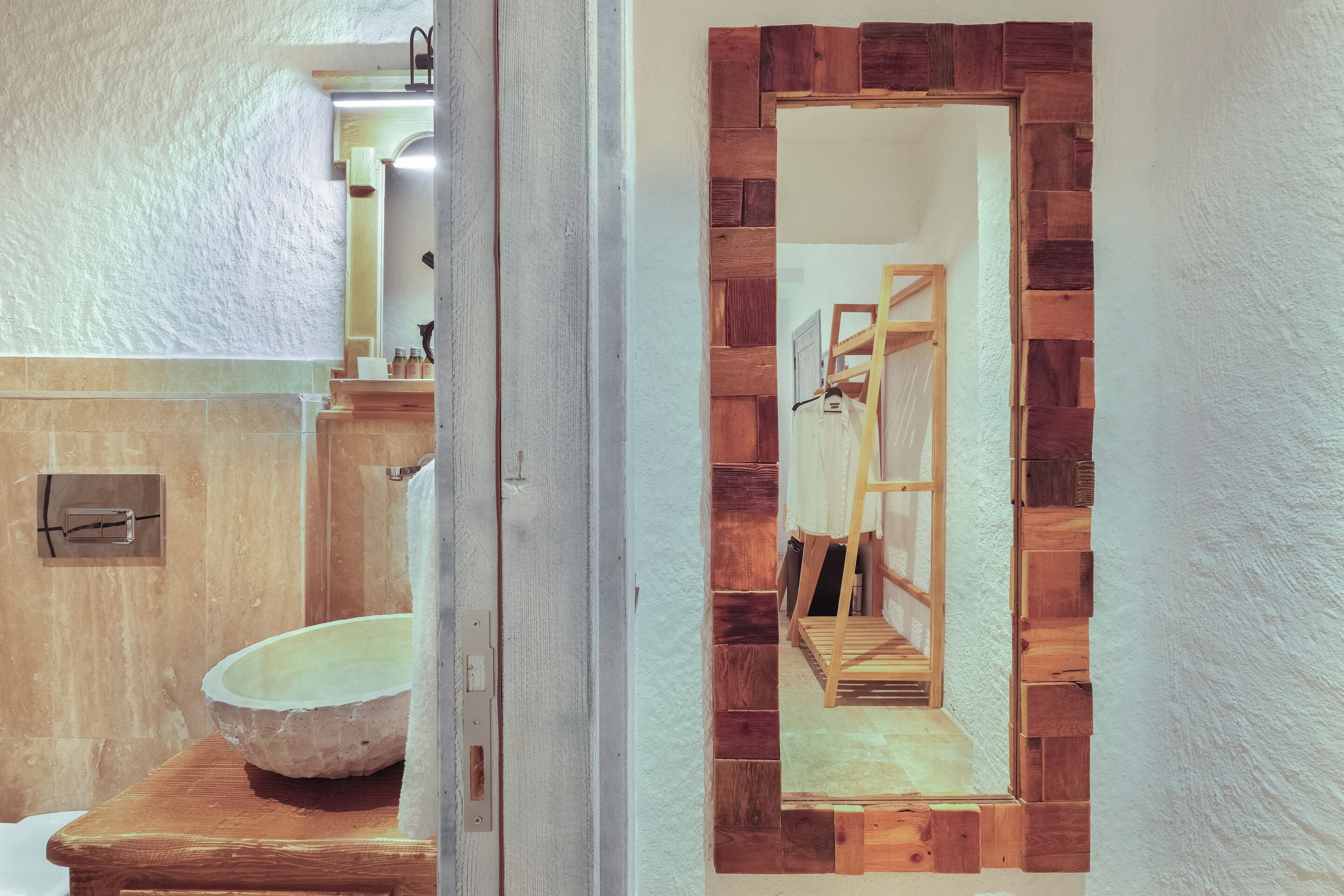Un baño con lavabo de piedra, tocador de madera y espejo con marco de madera.