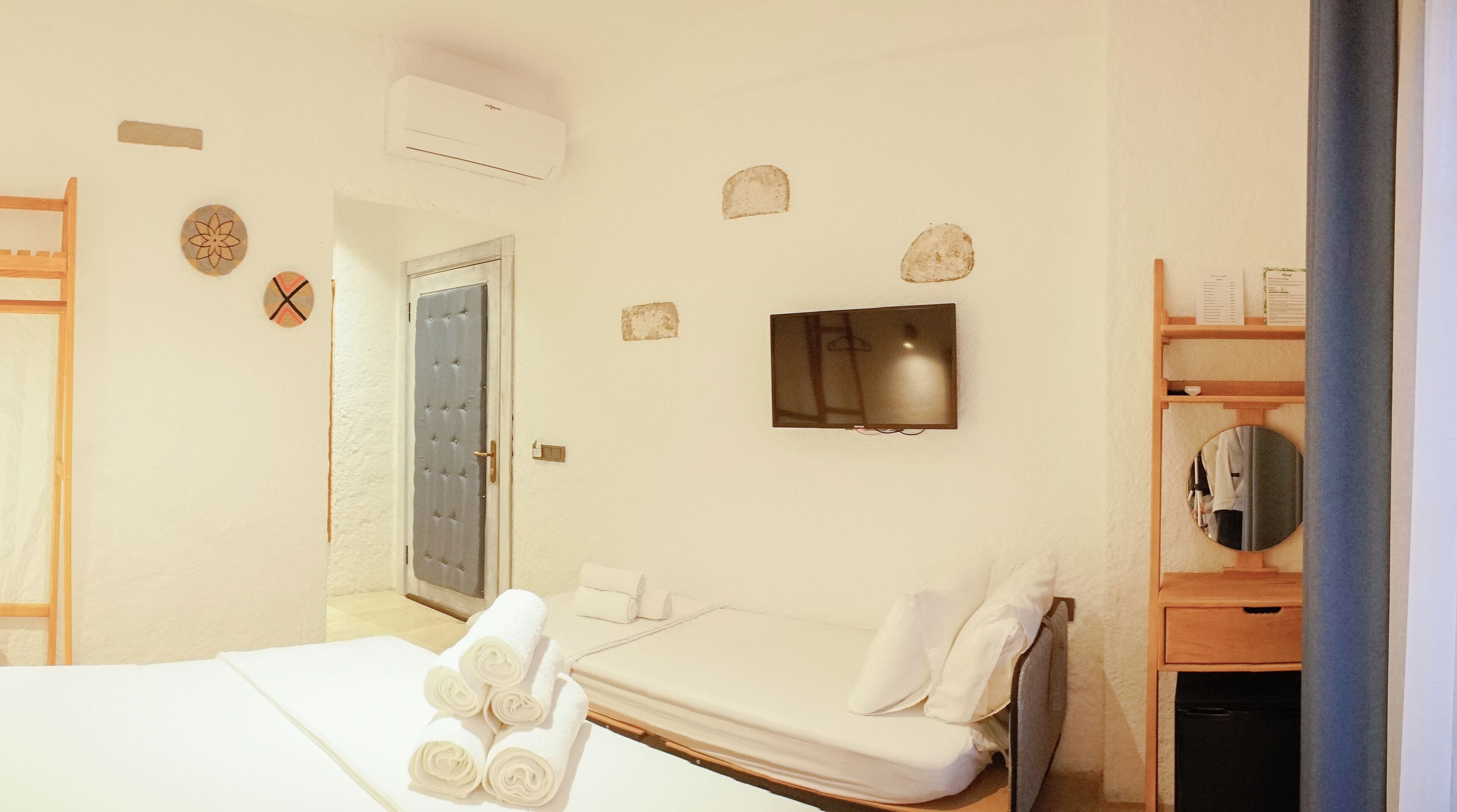 A hotel room with a bed, a TV, a wardrobe, and a mirror.
