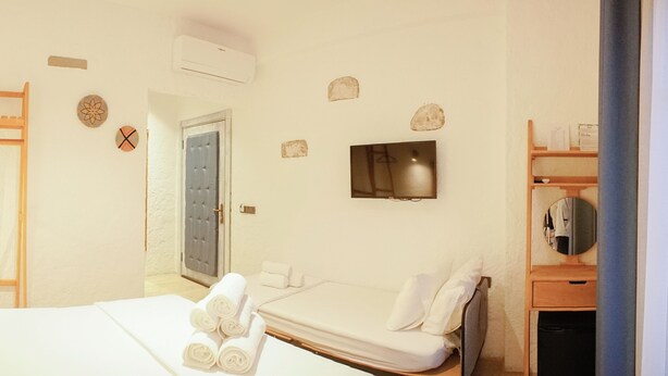 A hotel room with a bed, a TV, a wardrobe, and a mirror. - Armel Alacati (Cesme)