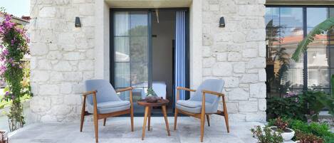 A stone building with a patio area featuring two chairs and a small table.