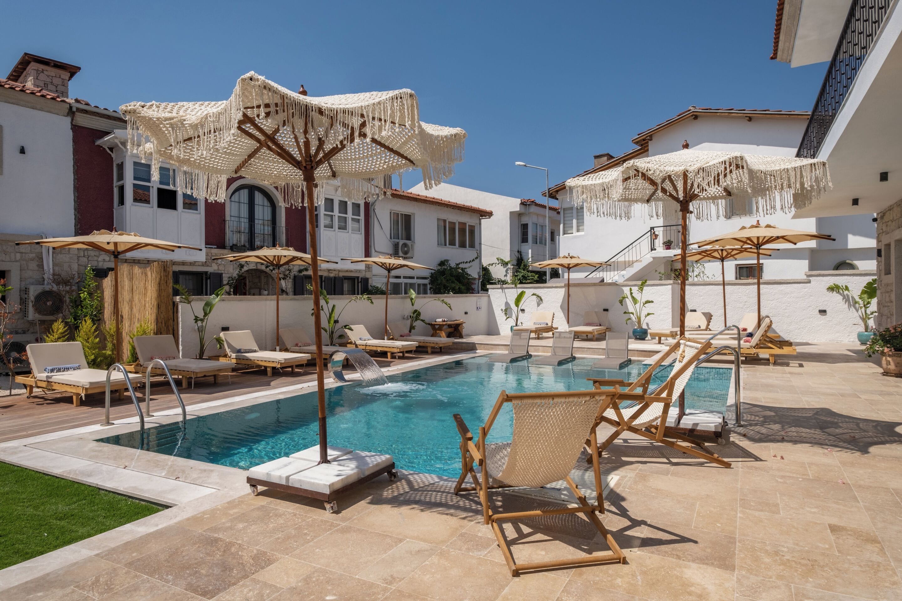 A pool area with lounge chairs and umbrellas, surrounded by buildings with balconies.