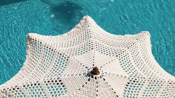 Una piscina al aire libre, una piscina climatizada, sombrillas
