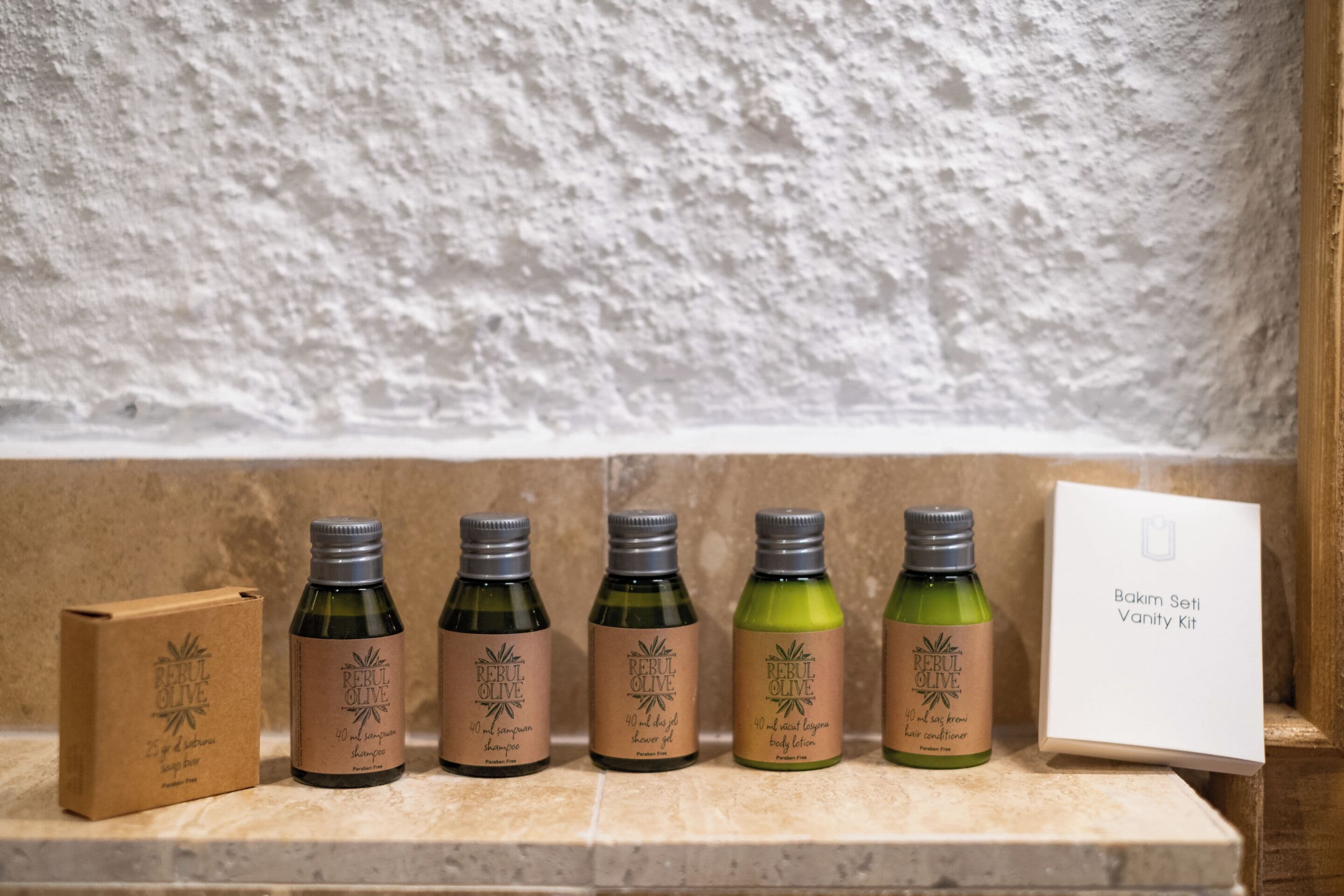 A shelf with five bottles of Reboul Olive hair care products and a box labeled "Bakim Seti Vanity Kit".