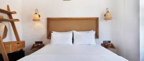 Una cama bien hecha con sábanas blancas, dos mesitas de noche con lámparas, y una escalera de madera apoyada contra la pared.