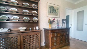 A wooden cabinet with multiple shelves and drawers, a telephone, and a vase with flowers. - Renovated French House - 2 bedroom with A/C (Brignais)