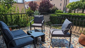 A patio with two lounge chairs and a small table, surrounded by a tiled floor and a metal railing. - Renovated French House - 2 bedroom with A/C (Brignais)