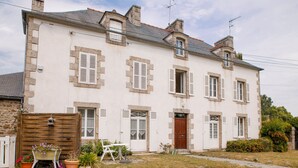 Ein zweistöckiges Gebäude mit symmetrischer Fassade, zahlreichen Fenstern mit Fensterläden und einem zentralen Eingangsbereich mit einer Tür.