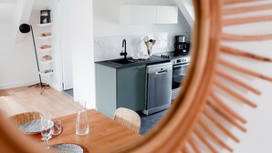 Eine moderne Küche mit Essbereich, mit einem Holztisch, Stühlen und einer schwarzen Pendelleuchte.