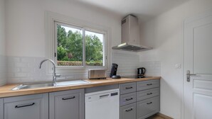 A modern kitchen with a dishwasher, a coffee maker, and a window with a view of greenery. - Relax and garden - Sleeps 6 - 550m from the beach (Saint-Gildas-de-Rhuys)