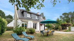 A house with a patio area featuring two lounge chairs, a table, and an umbrella. - Relax and garden - Sleeps 6 - 550m from the beach (Saint-Gildas-de-Rhuys)