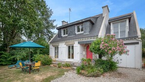 A two-story house with a gravel driveway, a patio with outdoor furniture, and a garden with flowering plants. - Relax and garden - Sleeps 6 - 550m from the beach (Saint-Gildas-de-Rhuys)