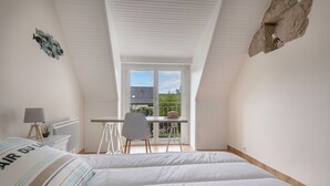 A bedroom with two beds, a desk, and a window overlooking a balcony. - Relax and garden - Sleeps 6 - 550m from the beach (Saint-Gildas-de-Rhuys)