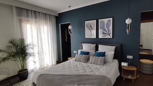 Ein modernes Schlafzimmer mit einem großen Bett, einem Blumentopf, einem Sessel und Kunstwerken an den Wänden.