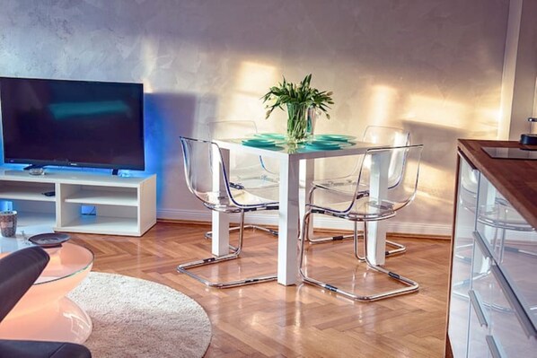 Relax in this stylish living room with a flat-screen TV, glass-top coffee table, and comfortable seating.