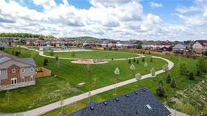 A residential area with houses, a central green space with a playground, and a curved driveway.