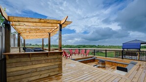 A wooden deck with a covered seating area, outdoor furniture, and a view of the landscape.
