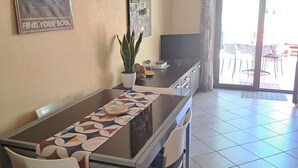 Un área de comedor con una mesa, sillas, una planta en maceta, un televisor de pantalla plana y un cartel en la pared.