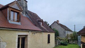 Ein traditionelles Haus mit Satteldach, einem sichtbaren Schornstein und einem kleinen Vorgarten mit weißem Geländer.