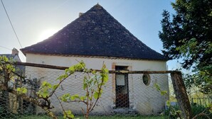 Ein Gebäude mit einem Satteldach, einer kleinen Tür und einem Maschendrahtzaun im Vordergrund.
