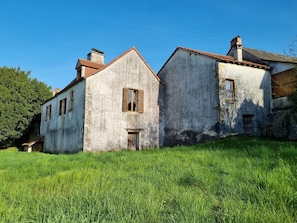 A two-story building with a sloped roof, a small window with shutters, and a door.