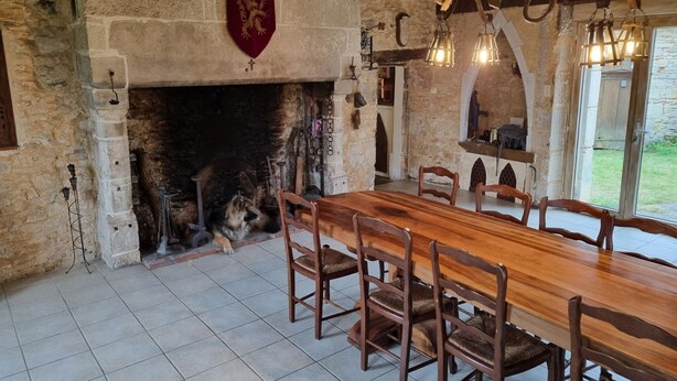 Ein rustikaler Essbereich mit Kamin aus Stein, Holztisch und Stühlen.