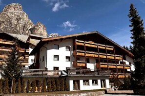 Un hôtel à plusieurs étages, doté de balcons en bois et surplombant un paysage montagneux.