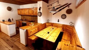 A kitchen with wooden cabinets, a central island, and a hanging light fixture. - The perfect retreat for those seeking peace, comfort, sports and nature (Corvara in Badia)