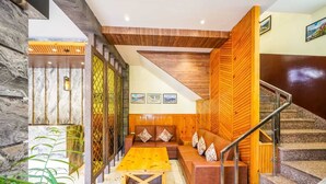Un hall d’entrée moderne avec un comptoir d’accueil en bois, un espace salon et un escalier.