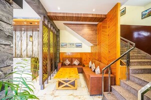 Un lobby moderno con un mostrador de recepción de madera, un área de descanso y una escalera.