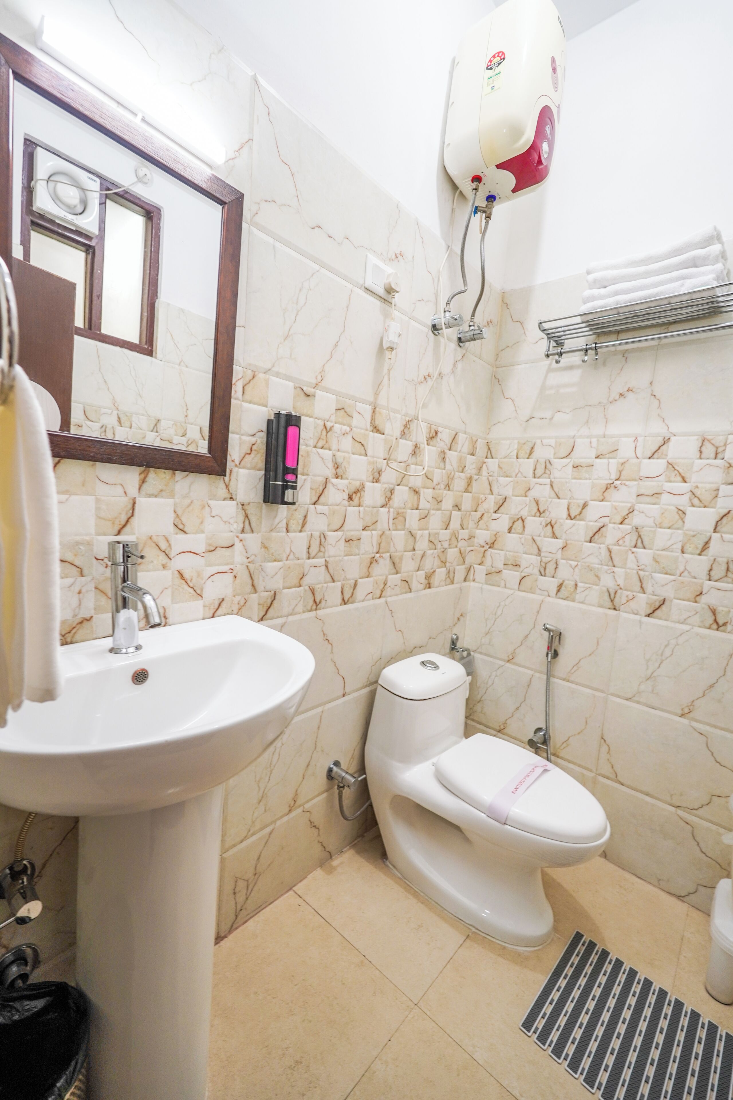 A bathroom with a sink, toilet, and a water heater mounted on the wall.