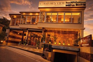 Un hotel llamado 'Nature's View' con un diseño moderno, ventanas grandes y una entrada acogedora.