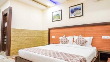 Habitación de hotel con cama, ventilador de techo, aire acondicionado y cuadros en la pared.