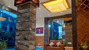 Un hall d’entrée avec un pilier en pierre, un canapé en cuir marron et un grand luminaire au plafond.