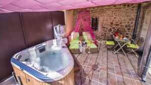 Un jacuzzi, mobiliario de mimbre y una pared de piedra.