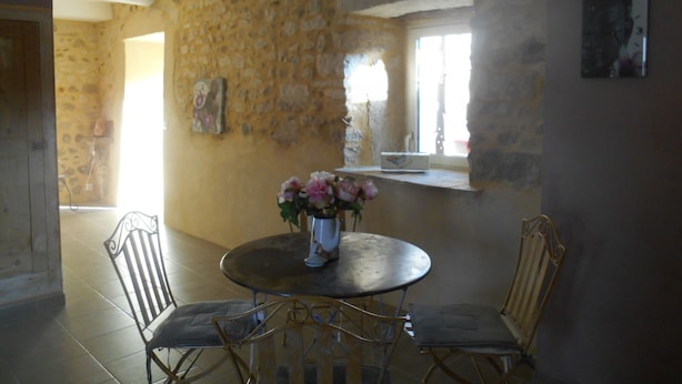 Un comedor con pared de piedra, una mesa redonda y cuatro sillas.