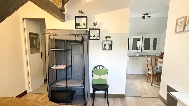Un espace de vie compact comprenant un lit superpos é, une petite table et une chaise. On aperçoit une kitchenette au fond.