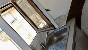 Une salle de bain avec un lavabo, un miroir et une fenêtre.