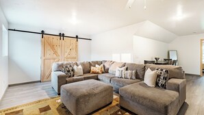 Un amplio salón con un sofá modular grande, otomanas y una alfombra estampada.