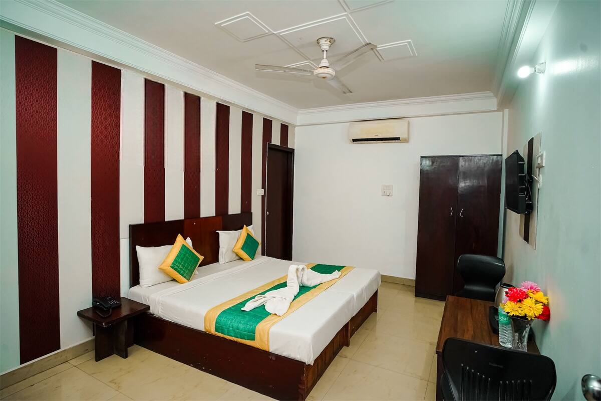 Une chambre d’hôtel équipée d’un lit, d’un bureau, d’une chaise, d’une télévision et d’un appareil de climatisation.